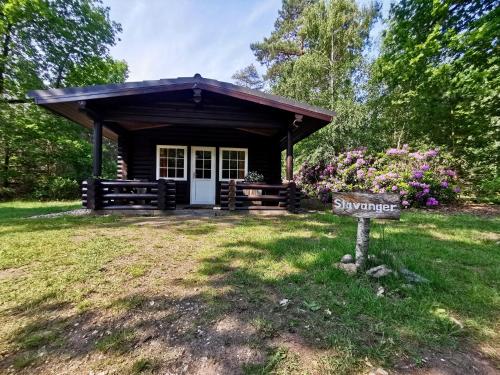 a small cabin with a sign in the grass at Scandinavian Lodges (by Outdoors Holten) in Holten