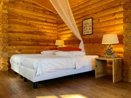 una camera con un letto in una baita di tronchi di Scandinavian Lodges (by Outdoors Holten) a Holten