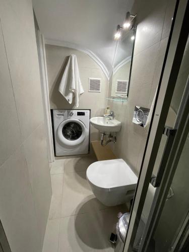 a bathroom with a toilet sink and a washing machine at Kalimera Alimos Apartment in Athens