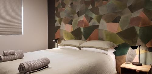 1 dormitorio con 1 cama grande y pared colorida en Brookside Central Wanaka Luxury Apartment, en Wanaka