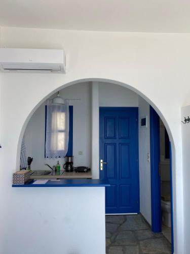 cocina con puerta azul y fregadero en Cavos Studio by the sea (West) en Drios