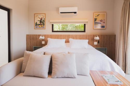 a bedroom with a bed with white sheets and pillows at Øko Villa in Juquei