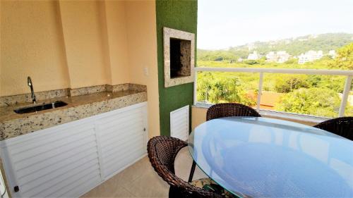 eine Küche mit Tisch und Stühlen und einem Fenster in der Unterkunft 1024 - Apartamento em Bombinhas para locação de temporada - Praia de Bombas in Bombas