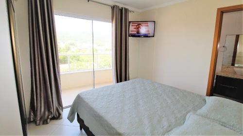 ein Schlafzimmer mit einem Bett und einem großen Fenster in der Unterkunft 1024 - Apartamento em Bombinhas para locação de temporada - Praia de Bombas in Bombas