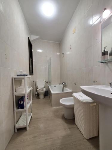 een badkamer met 2 toiletten, een bad en een wastafel bij Piso termal III in Ourense