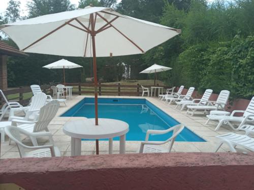 a table with an umbrella next to a pool at La Palapa ApartHotel in Villa General Belgrano