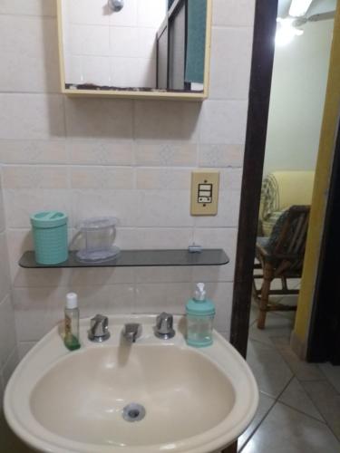 lavabo blanco en el baño con espejo en Condomínio agradável Familiar, en Matinhos