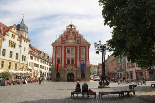 two people sitting on benches in front of a building at Pension Der kleine Nachbar in Gotha