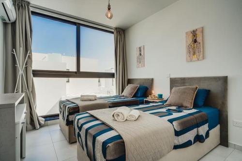 two beds in a room with a large window at SunnyVillas 4BR New Villa Private Pool in Pernera in Protaras