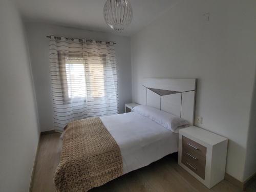 een witte slaapkamer met een bed en een raam bij Piso termal III in Ourense
