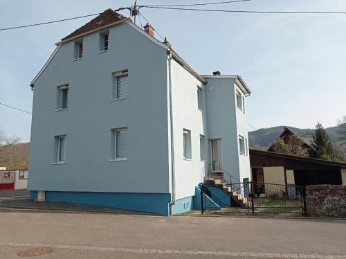 een wit gebouw met blauwe verf aan de zijkant bij Gite du moulin in Gunsbach
