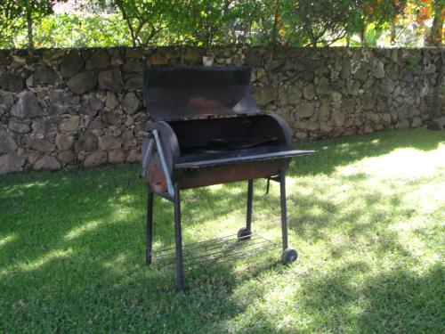 a grill sitting in the grass next to a stone wall at Las Casitas Tepoztlán in Tepoztlán