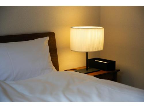 a bed with a lamp on a table next to it at Halettohouse SAKANOSHITA - Vacation STAY 30106v in Kamakura