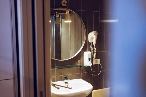 bagno con lavandino, specchio e telefono di LoL Hostel Siracusa a Siracusa