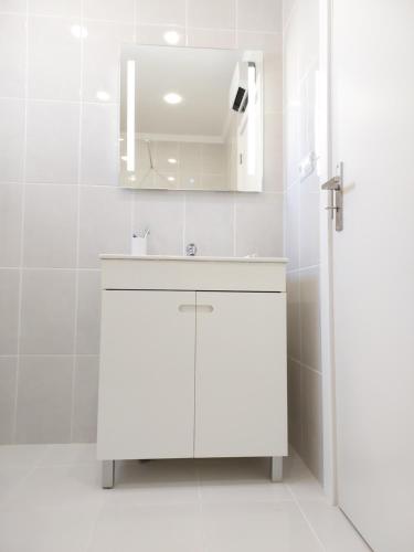 Baño blanco con lavabo y espejo en Sea View 3, en Albufeira