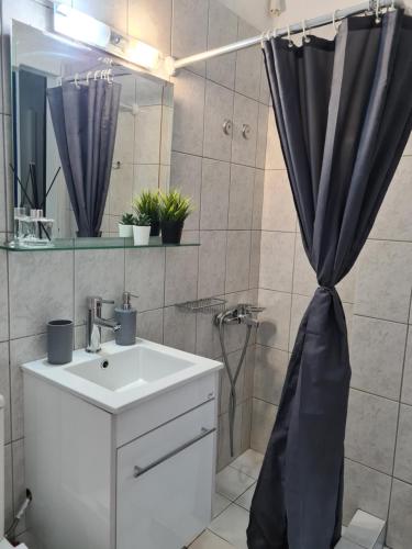 a bathroom with a sink and a shower curtain at Apartment in the heart of the city 3 in Larisa