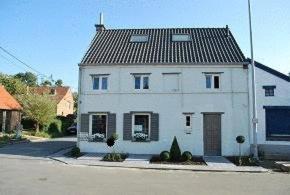 a white house with a black roof on a street at Sino in Dendermonde