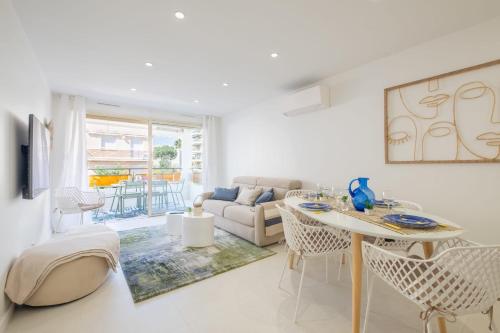 un salon blanc avec une table et des chaises dans l'établissement Stylish 2-Br Apartment Steps from the Croisette, à Cannes