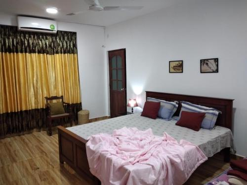 a bedroom with a large bed with pink sheets at Kuma Beach side Villa in Wadduwa
