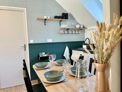 una mesa de comedor con platos y copas de vino en Émeraude Lumineux T3 au cœur du village, à 5 min des plages, en Saint-Méloir-des-Ondes