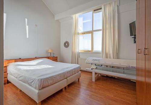 a white bedroom with a bed and a window at Appartementen De Buteriggel in De Koog