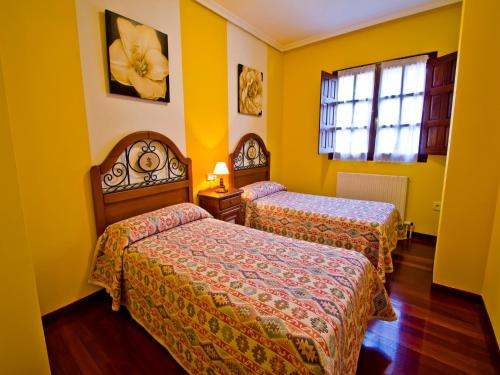 two beds in a room with yellow walls at Apartamento EL RINCON DE MARIA in Santillana del Mar
