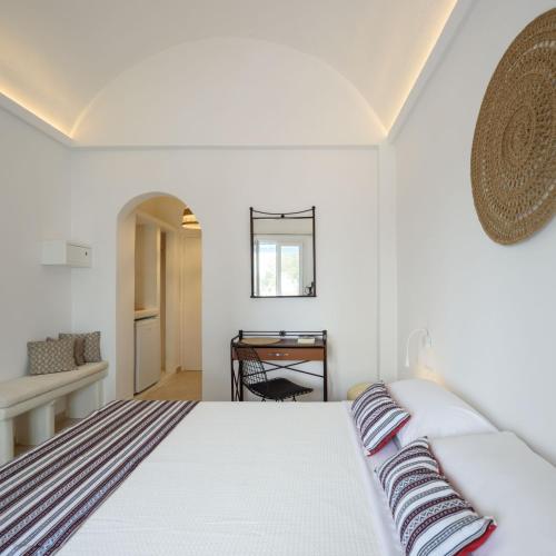 a white bedroom with a bed and a desk at Cal Day Rooms Santorini in Perissa