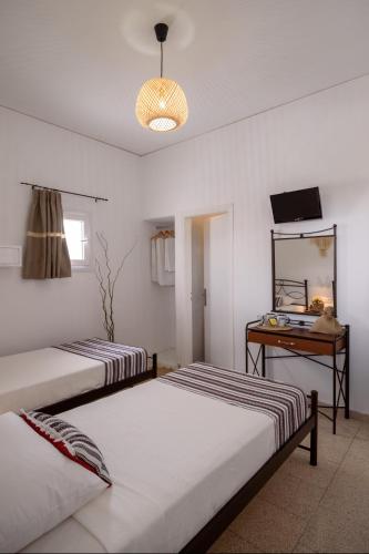 two beds in a room with a table and a mirror at Cal Day Rooms Santorini in Perissa