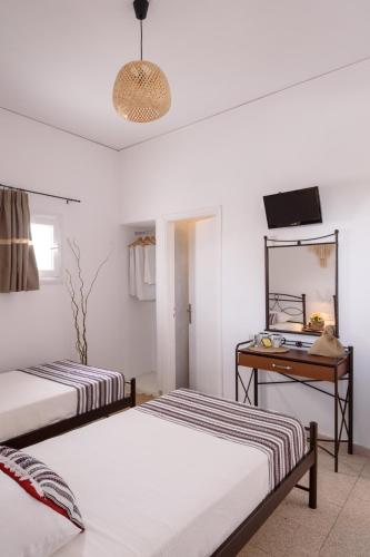 two beds in a room with a table and a mirror at Cal Day Rooms Santorini in Perissa