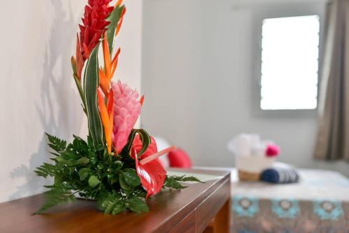 a vase of flowers sitting on top of a table at Les jardins de CHANTILLY -Bungalows 4 étoiles avec jardins et piscines privées in Baie-Mahault
