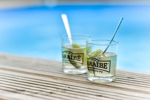 two glasses of orange juice sitting on a wooden table at Les jardins de CHANTILLY -Bungalows 4 étoiles avec jardins et piscines privées in Baie-Mahault