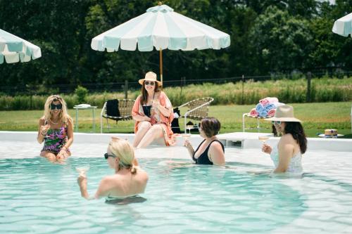 a group of women sitting in a swimming pool at The Frenchie in Round Top