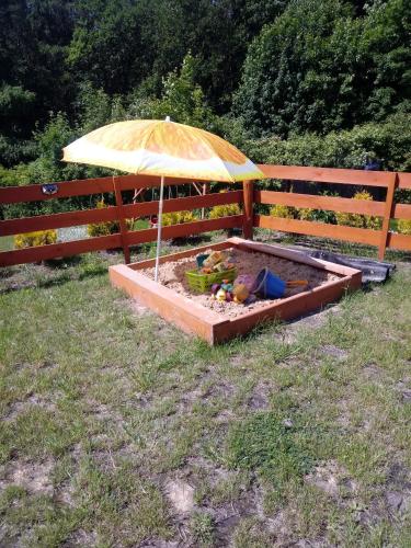 a sandbox with an umbrella in front of a fence at Roztocze, Domek Na Leśnym Wzgórzu nr2,Krasnobród,Zamość, Zwierzyniec, jacuzzi in AdamÃ³w