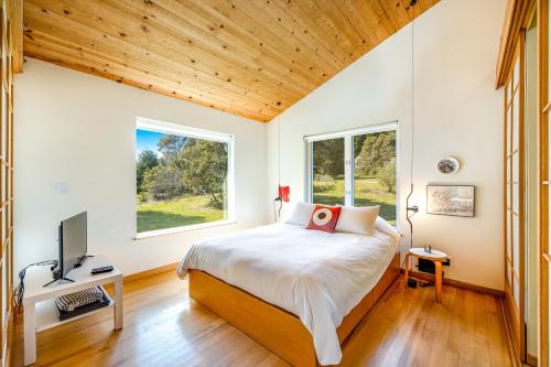 une chambre avec un lit, une télévision et des fenêtres dans l'établissement Madrone Cottage, à Sea Ranch