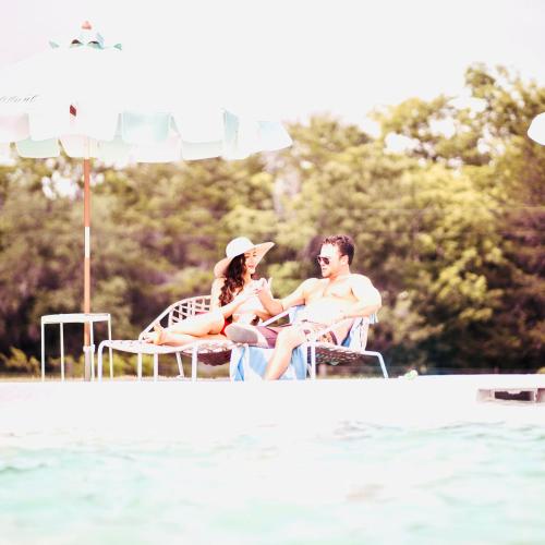 a man and a woman sitting on chairs next to the water at The Frenchie in Round Top