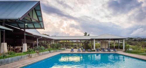 a swimming pool with chairs and a house at Sands Beach Simbithi Eco Estate Luxury Villa in Ballito