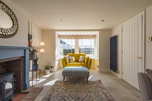 een woonkamer met een gele bank en een open haard bij Wheelwrights Cottage by Bloom Stays in Staple Cross