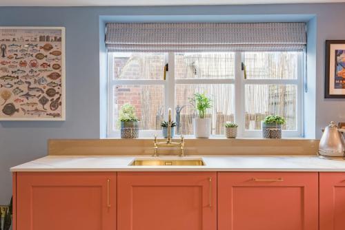uma cozinha com um lavatório e duas janelas em Wheelwrights Cottage by Bloom Stays em Staple Cross