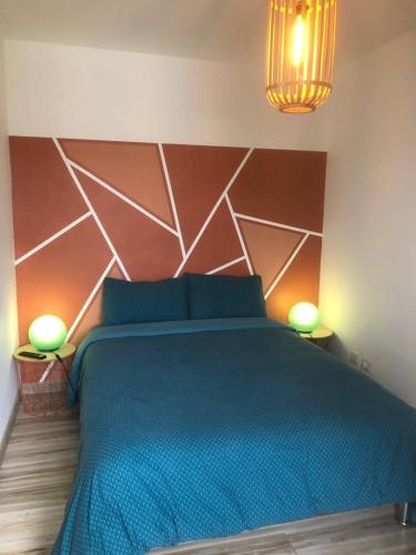 una camera da letto con un grande letto blu con due lampade di Appartement Perros-guirec petite terasse vue mer. a Perros-Guirec