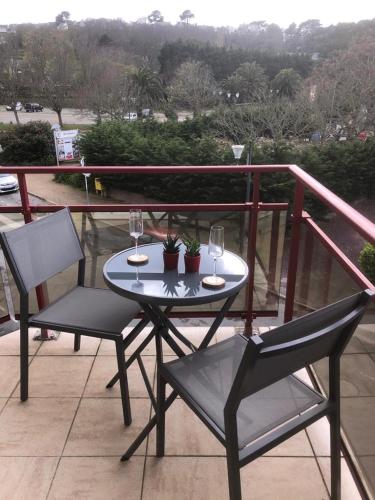 uma mesa com 2 cadeiras e copos de vinho numa varanda em Appartement Perros-guirec petite terasse vue mer. em Perros-Guirec