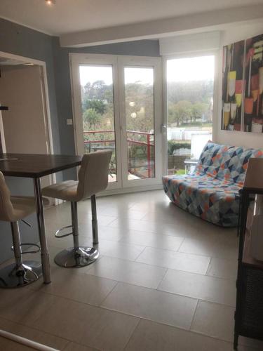 un soggiorno con tavolo, sedie e divano di Appartement Perros-guirec petite terasse vue mer. a Perros-Guirec