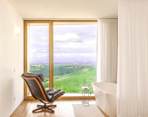 baño con silla, bañera y ventana en Casas Da Lapa, Nature & Spa Hotel en Seia