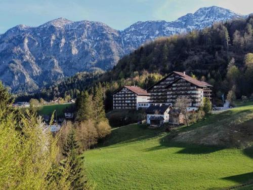 ein Haus auf einem grünen Feld mit Bergen im Hintergrund in der Unterkunft Almara - Family Apartment in Bad Goisern