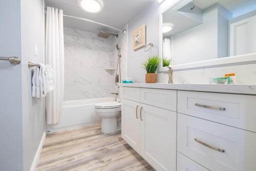 a white bathroom with a toilet and a sink at Ocean & Diamond Head Views - Near Beach - Parking! in Honolulu
