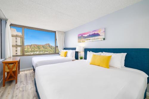 two beds in a hotel room with a large window at Ocean & Diamond Head Views - Near Beach - Parking! in Honolulu