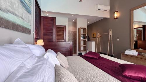 a bedroom with a large bed with white and purple pillows at Wood Chic in Baie-Mahault