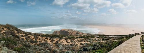 a boardwalk leading to a beach with a mountain at Casa Nook Sagres in Vila do Bispo