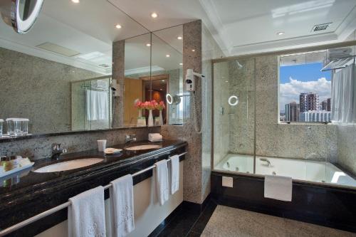 a bathroom with two sinks and a bath tub at Windsor Barra Hotel in Rio de Janeiro