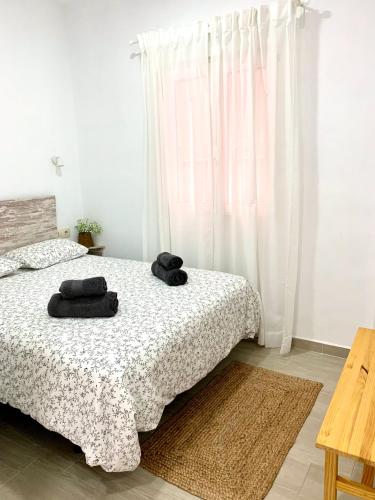 a bedroom with a bed with two black towels on it at Apartamento Puerta Al Mar in Tarifa