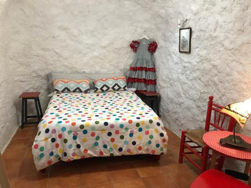a bedroom with a bed and a dress hanging on a wall at CUEVA EL DUENDE in Granada
